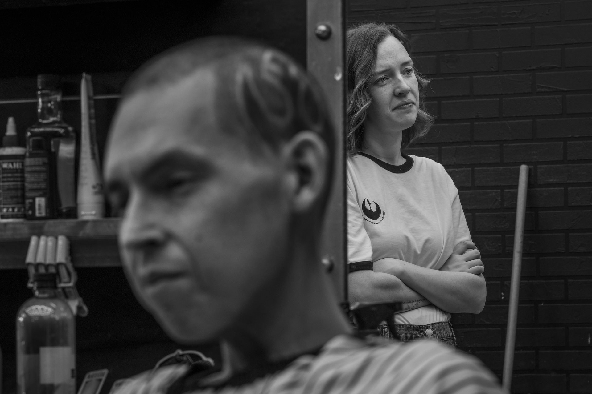 Shay Martin watches as a barber shaves a Star Wars symbol into Tanner&rsquo;s hair. Diagnosed at 25, Tanner represents &ldquo;Generation C&rdquo;; young adults facing a 200% to 300% increased risk of early-onset cancers compared to previous generations. Lehi, Utah, United States.